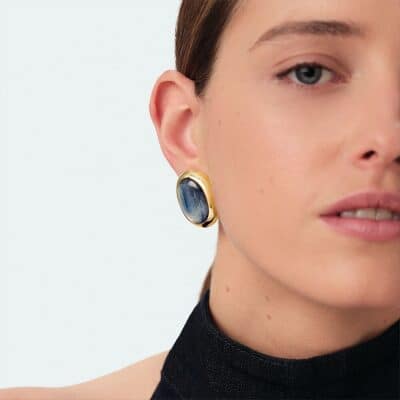 Boucles d'oreilles boutons collection RIVIERA, imaginées à Paris, réalisées en laiton doré 750/1000e - 18 carats et ornées de kyanite. Cette collection iconique met en valeur les pierres naturelles.